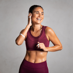 Smiling woman in maroon workout clothes jogging against a gray background