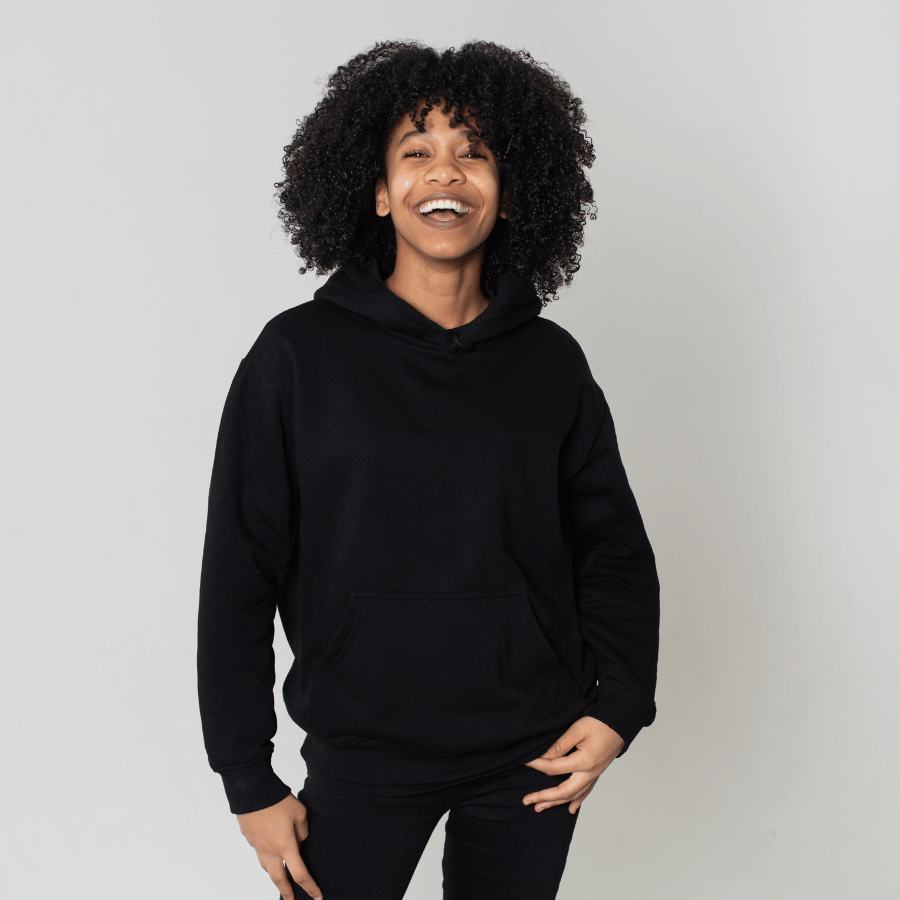 Person smiling in a black hoodie and pants against a light gray background