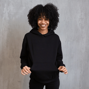Smiling person in a black hoodie standing against a gray backdrop