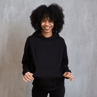 Smiling person in a black hoodie standing against a gray backdrop
