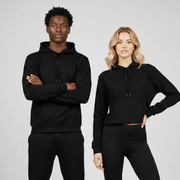 Two models in black hoodies and leggings posing against a light gray backdrop