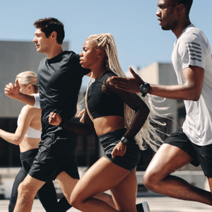 Runners sprinting outdoors in a group under bright sunlight