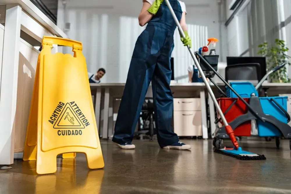 Yellow Caution Wet Floor Sign Near a Person Mopping an Office Floor — Jamac Cleaning Services in Merewether, NSW