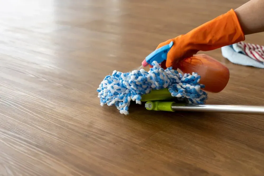 Gloved Hand Spraying Cleaner on a Mop Head — Jamac Cleaning Services in Wallsend, NSW