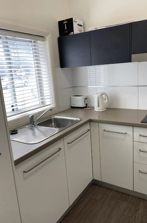 Small Kitchen With White Cabinets, Silver Sink, and Black Upper Cabinets — Jamac Cleaning Services in Cardiff, NSW