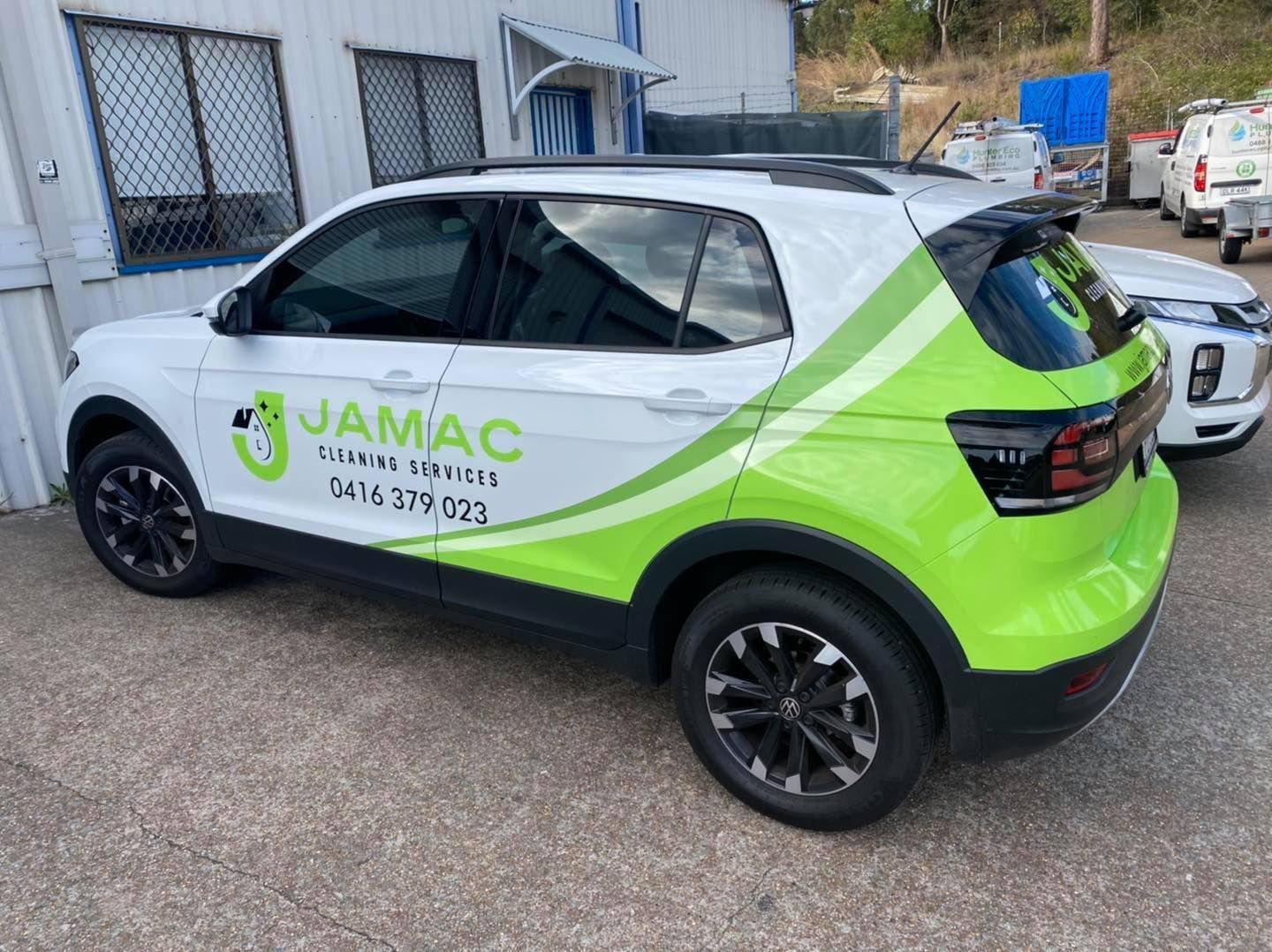 White and green JAMAIC-branded SUV parked on a street beside buildings