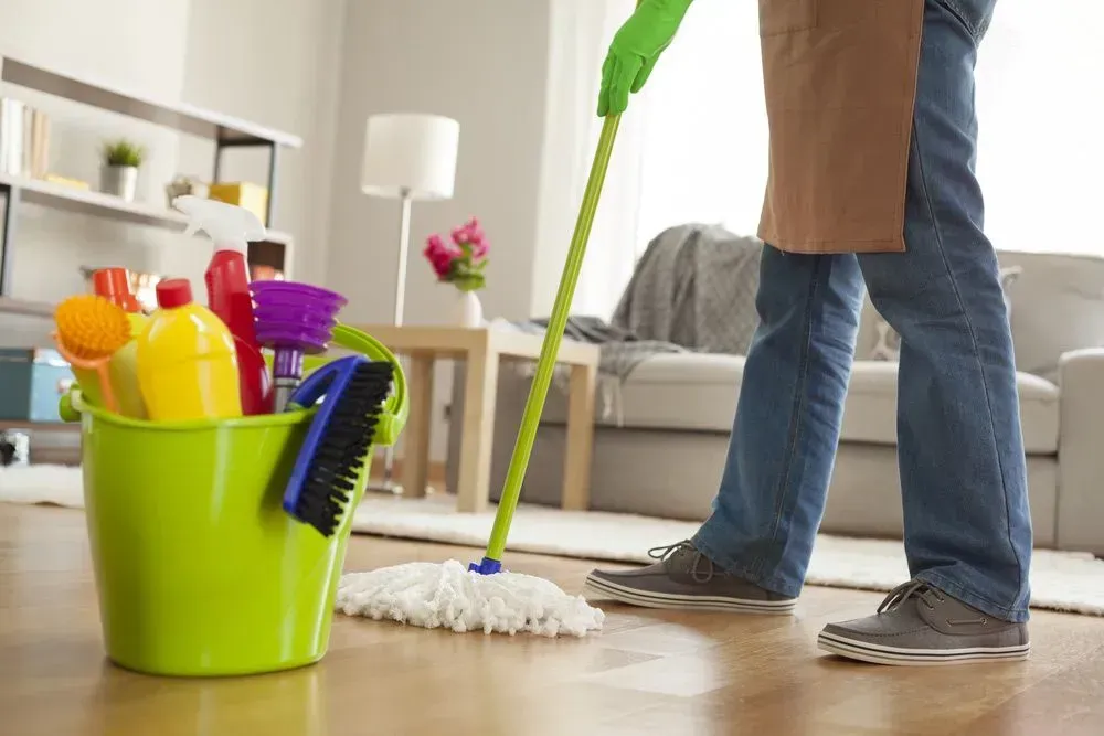 Person Mopping a Wooden Floor in a Living Room — Jamac Cleaning Services in Charlestown, NSW