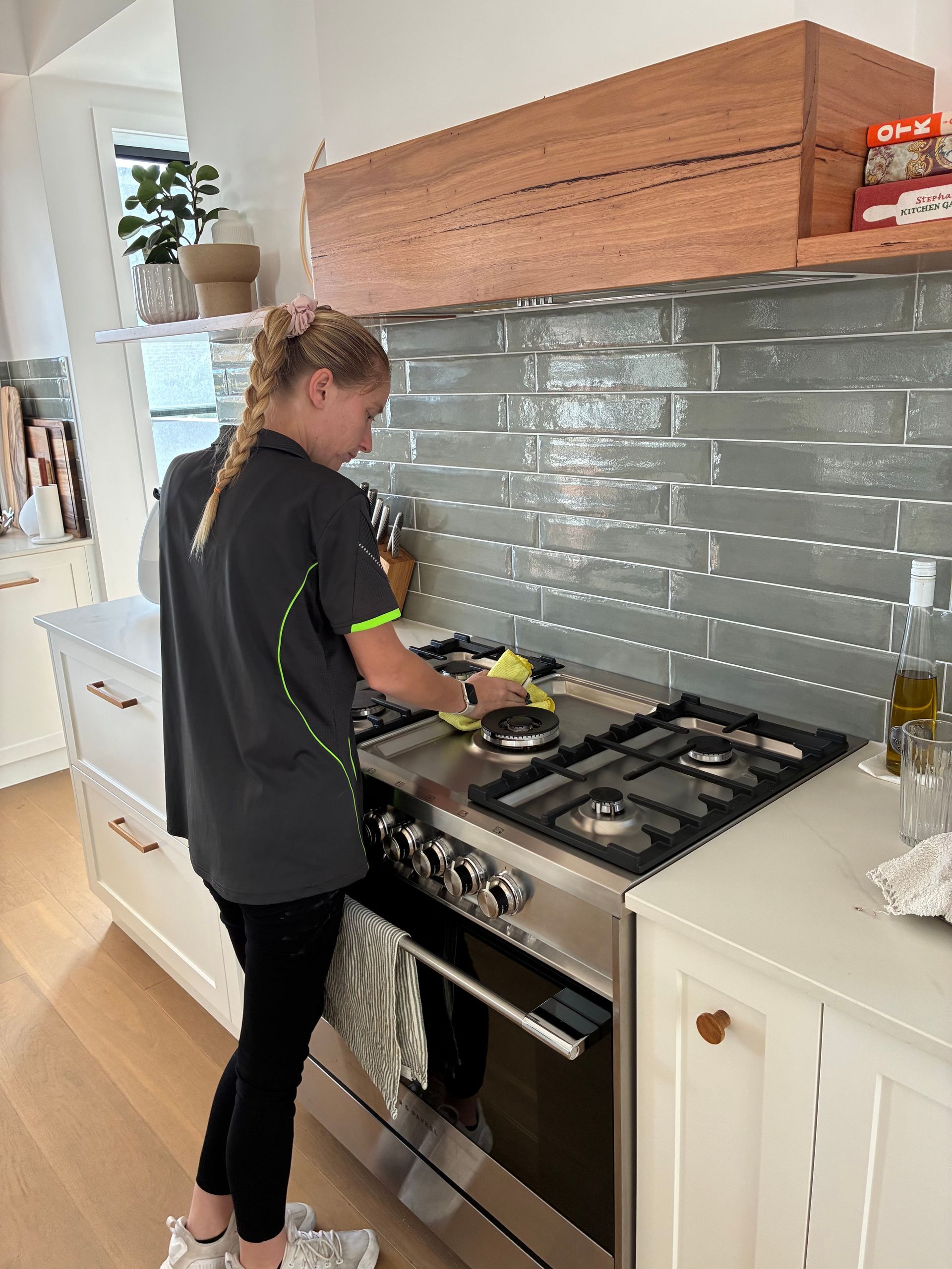 Person cooking at a stovetop in a bright kitchen with white cabinets and a gray tile backsplash