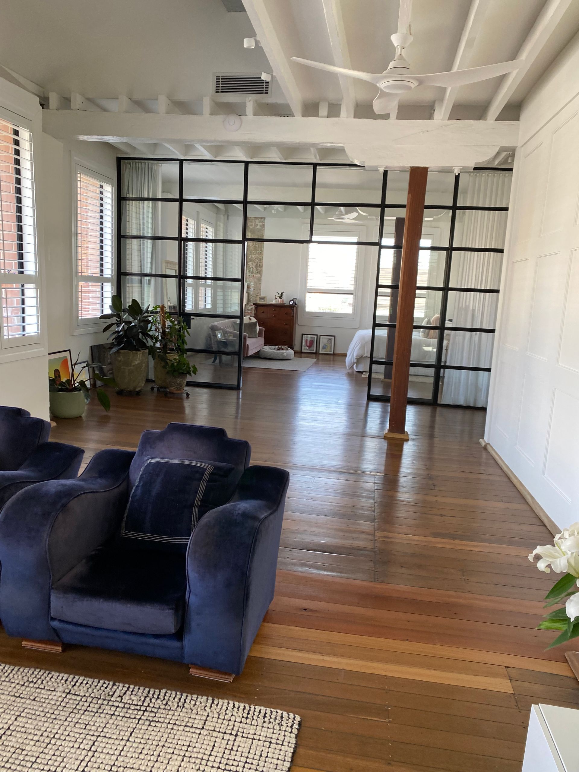 Spacious living room with navy sofa, wood floors, glass wall, and brick fireplace.