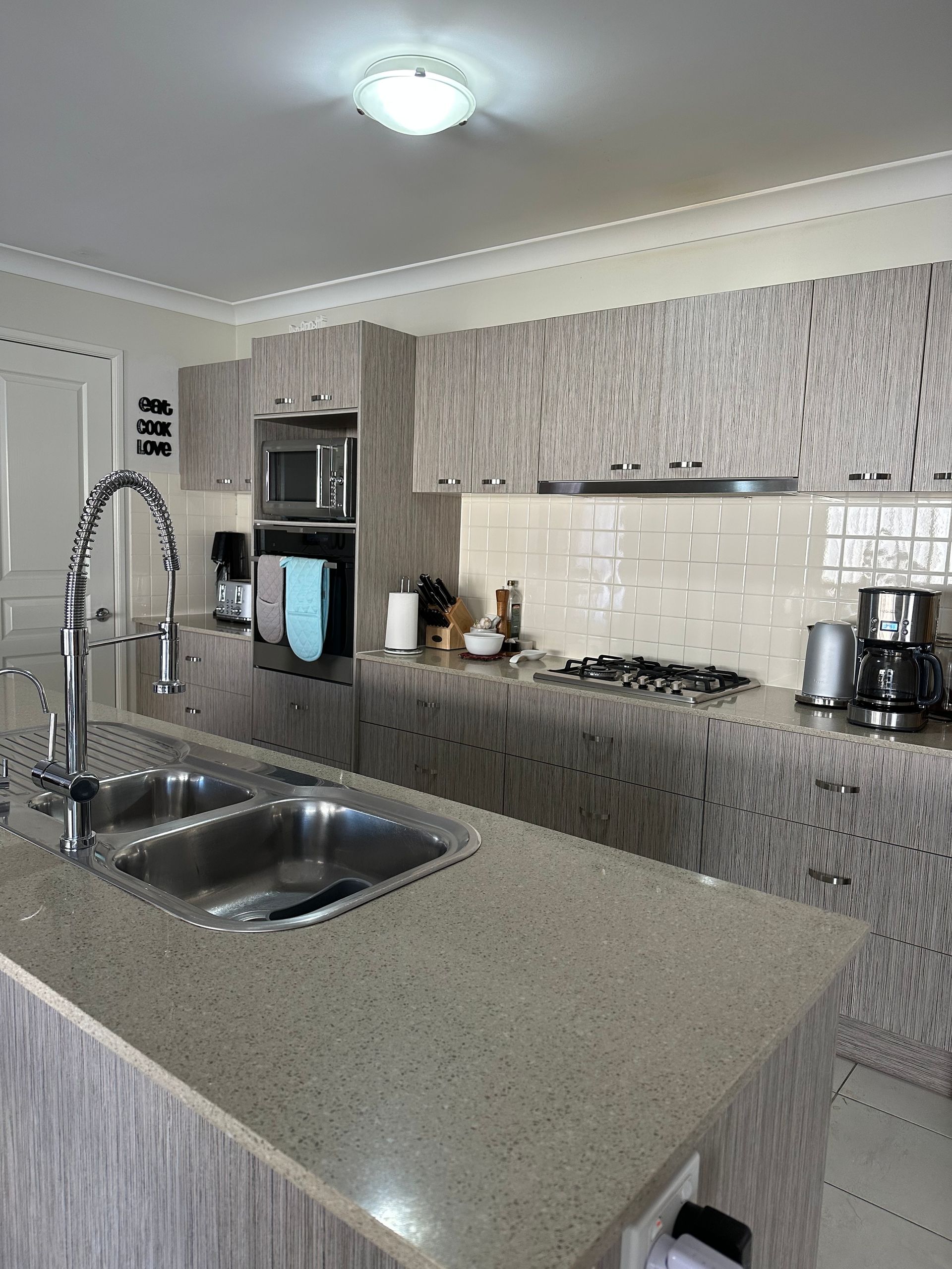 Modern kitchen with granite island, double sink, stainless appliances, and tiled backsplash