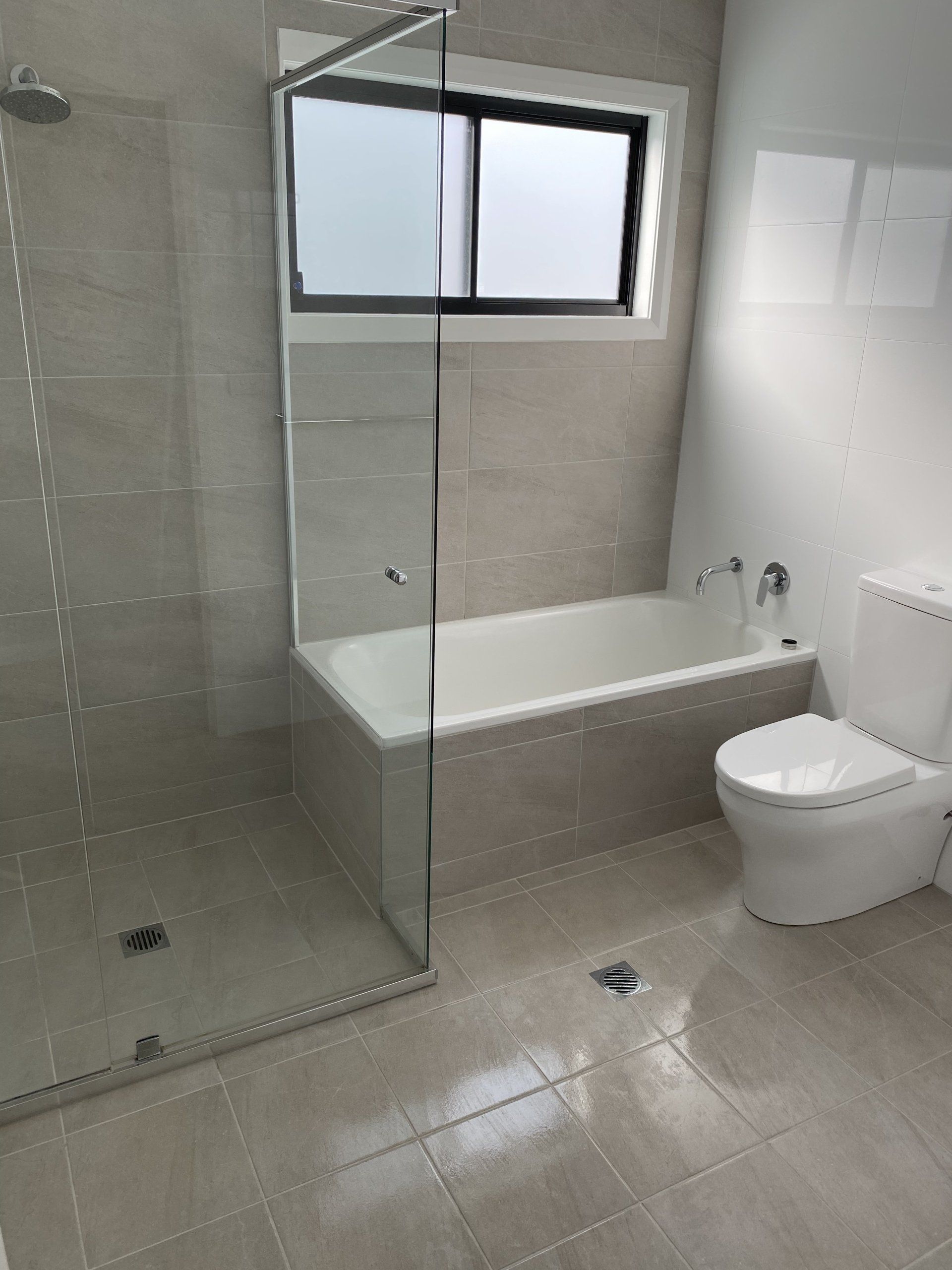 Bathroom With Shower, Bathtub, Toilet, and Window — Jamac Cleaning Services in Cardiff, NSW
