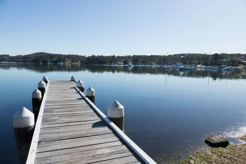 Wooden Dock Extending Into a Calm Lake Under a Clear Blue Sky — Jamac Cleaning Services in Lake Macquarie, NSW