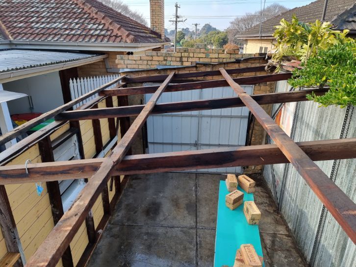 A wooden structure is being built in the backyard of a house.