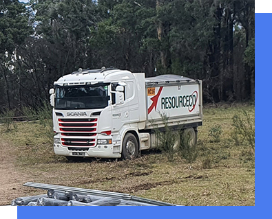 A white truck is parked in a field with trees in the background.