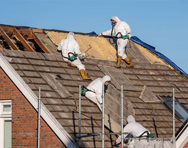 A group of people in protective suits are working on a roof.