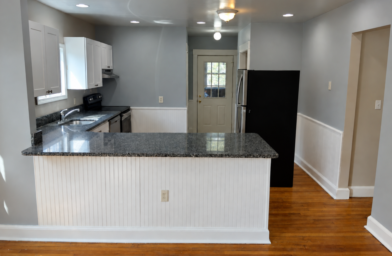 South Shore apartment kitchen after wall painting and a white cabinet refresh, with freshly painted trim and wainscoting.