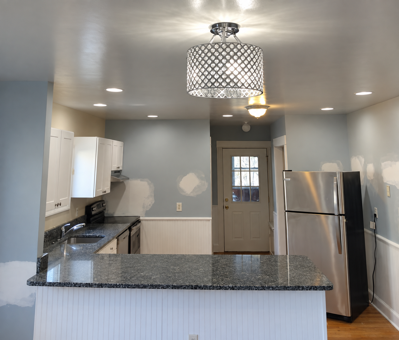Kitchen walls with patched holes and repaired areas before interior painting in a South Shore apartment.