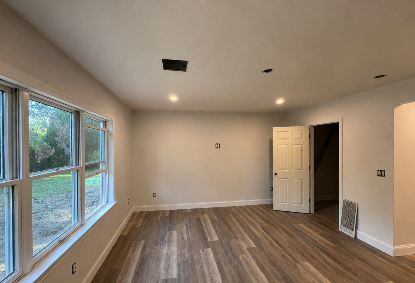 Empty room prepared for interior painting with bare walls and wood-look flooring in Dartmouth, Massachusetts