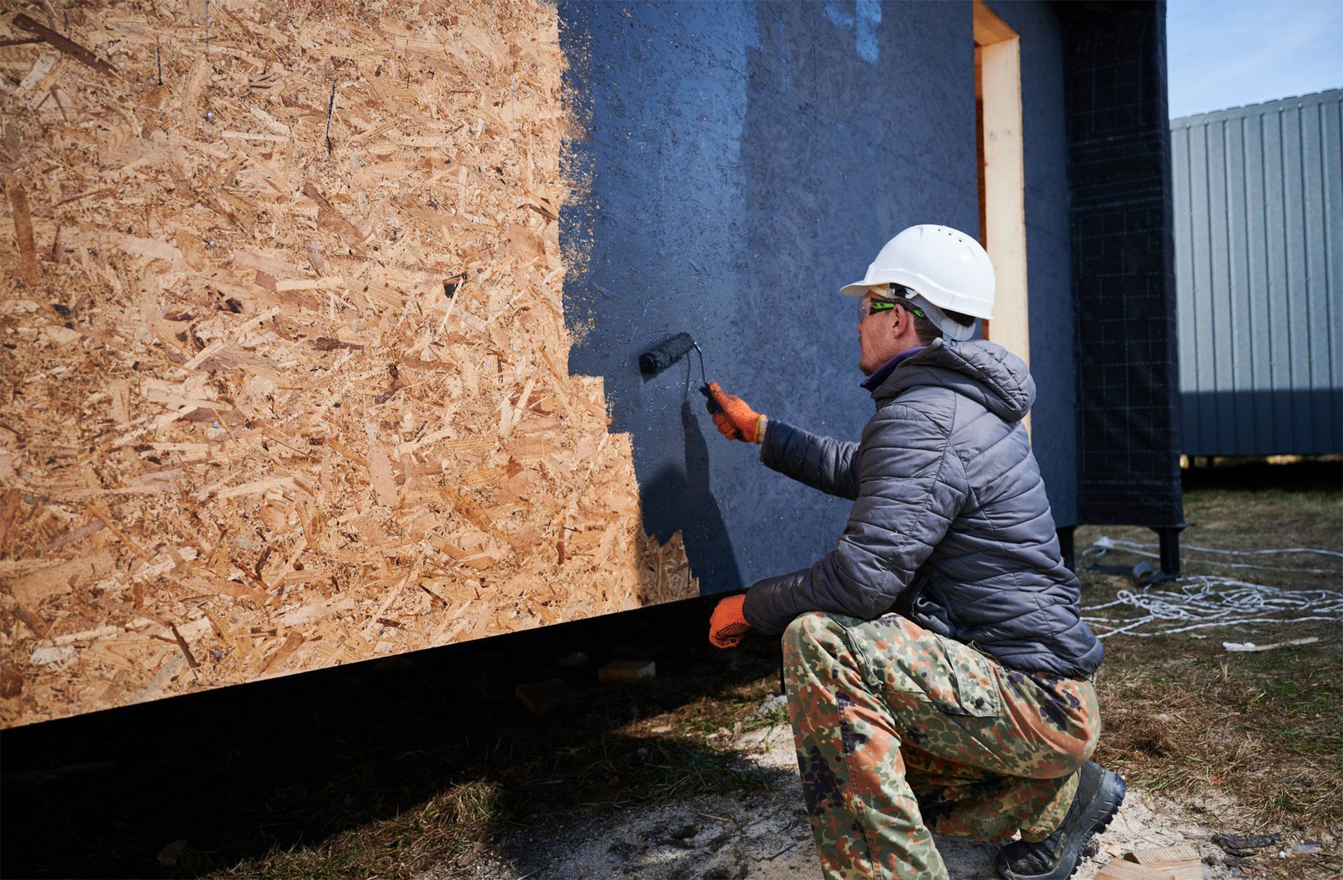 A man is painting a wall with a roller.