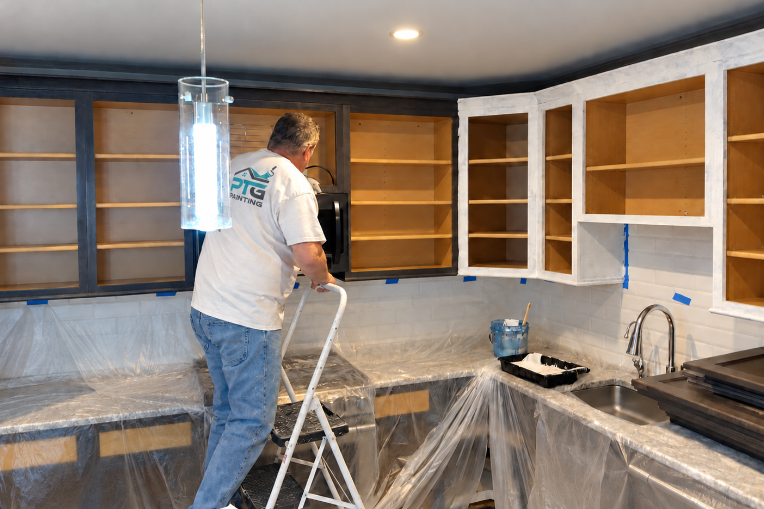 PTG Painting crew member preparing kitchen cabinets for painting while countertops and surrounding surfaces are protected in Braintree, MA.