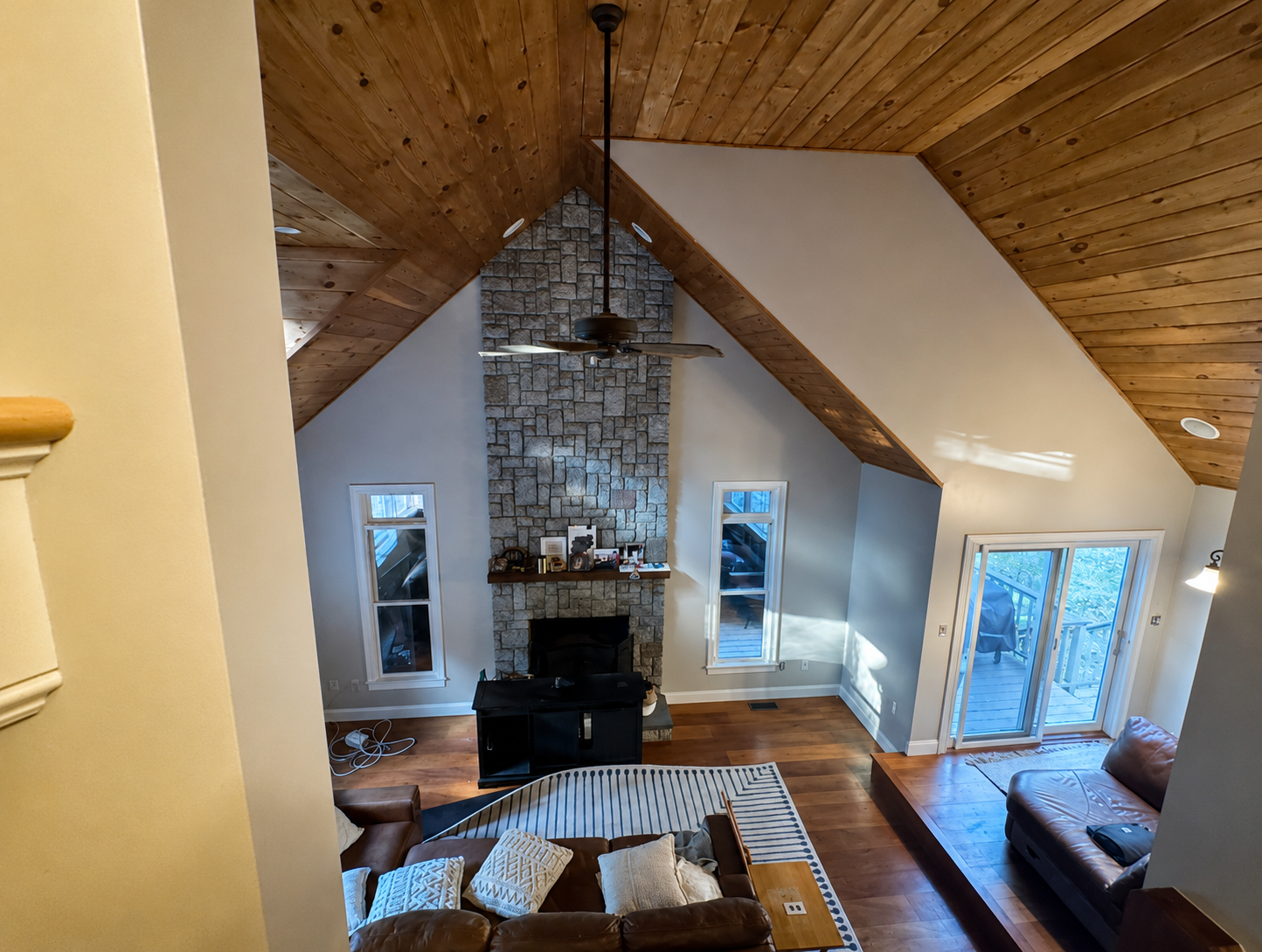 Freshly painted high-ceiling living room with a stone fireplace and wood-paneled ceiling in Norton,