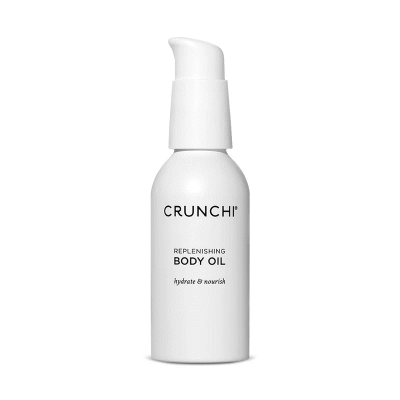 A white pump-top bottle of Crunchi Replenishing Body Oil with black text against a plain white background.