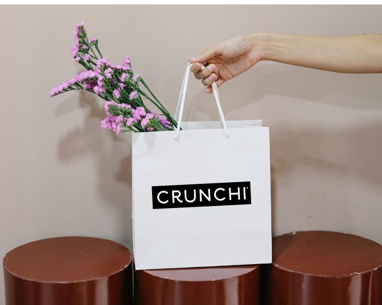 A person is holding a white bag with flowers in it.