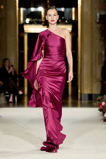 A woman in a purple dress is walking down a runway.
