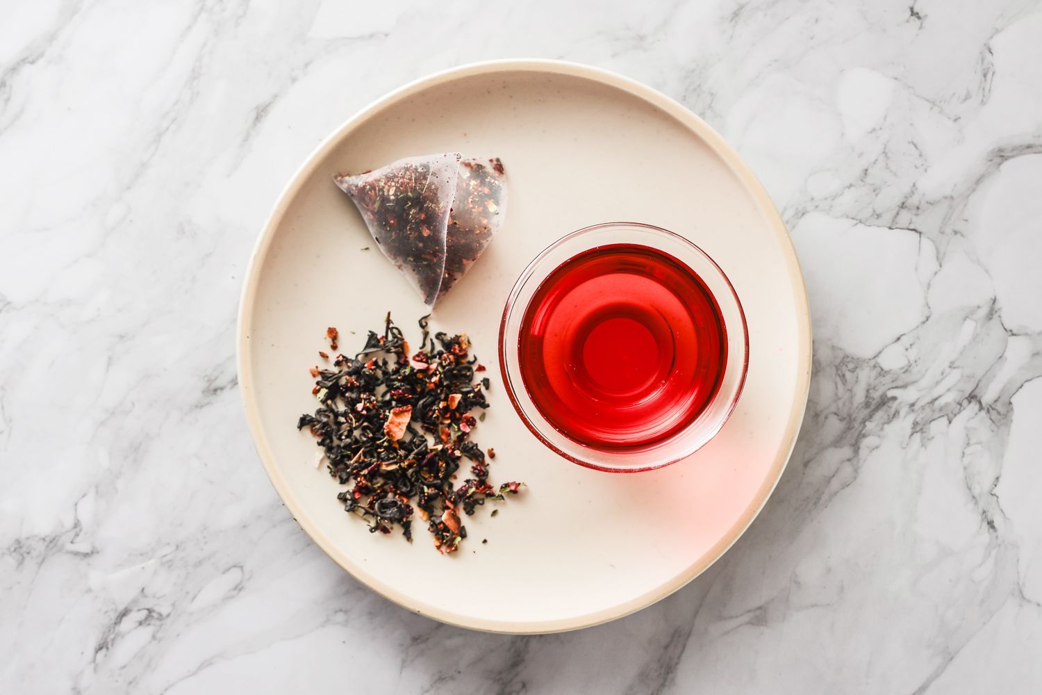 桌上放著一包草莓紅茶、一小碟乾茶葉和一杯泡好的紅茶。