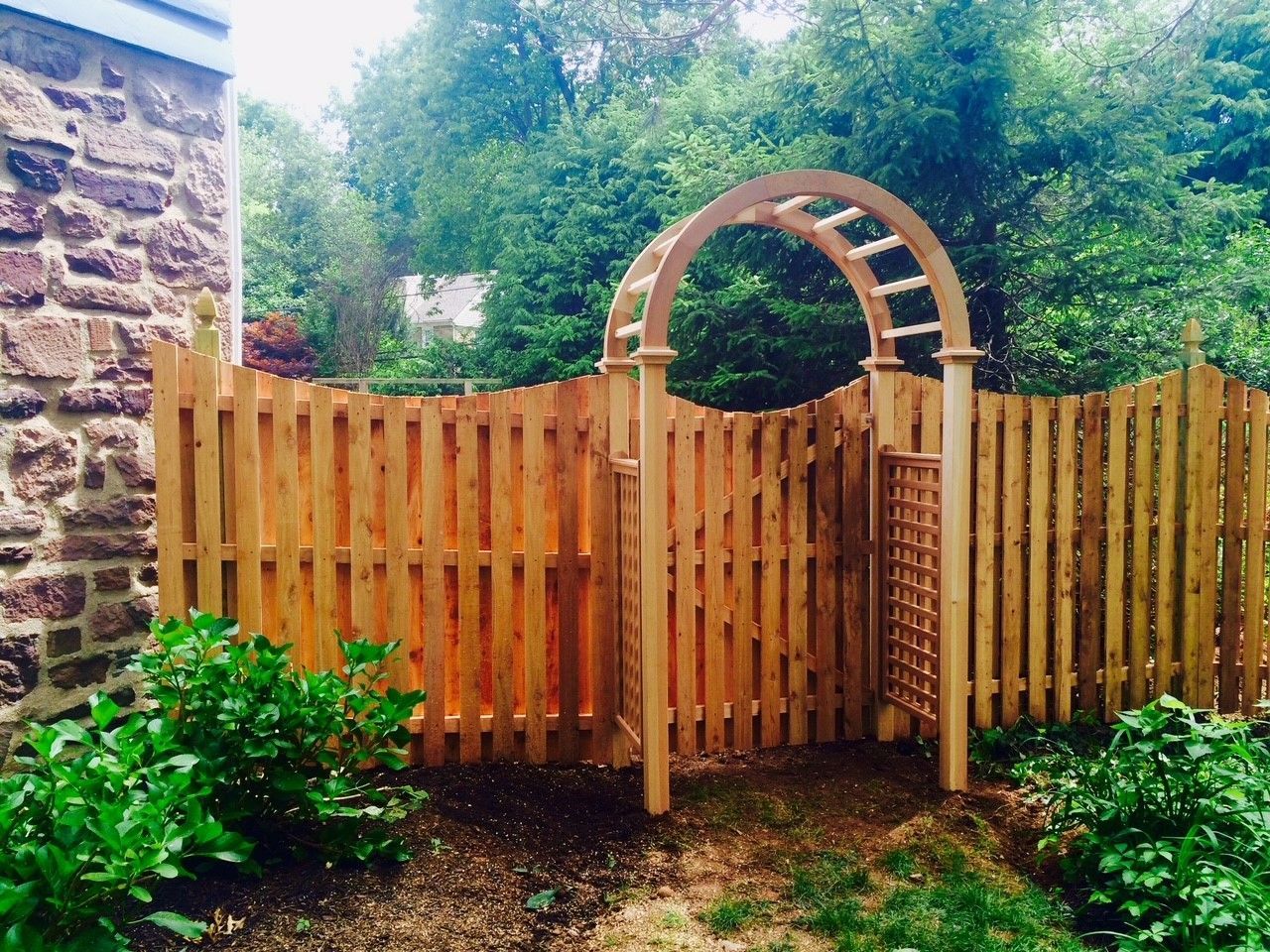 A wooden fence with a wooden arch in the middle of it.