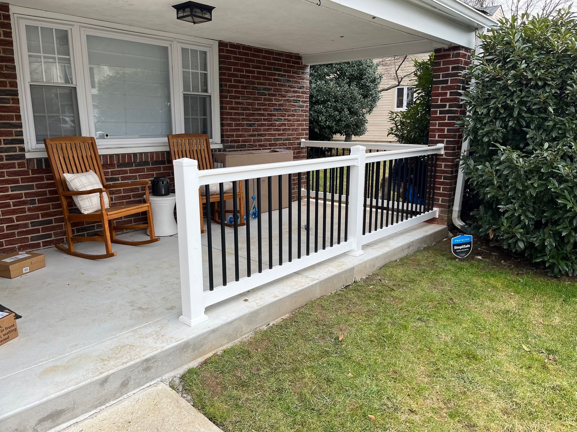 A porch with a white railing and rocking chairs on it.