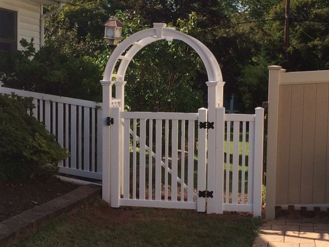A white fence with a gate in front of a house