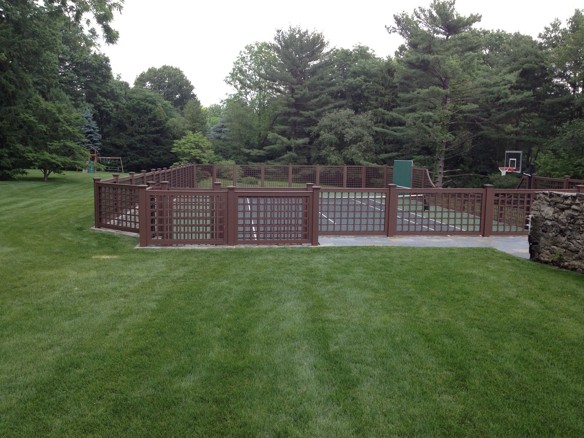A wooden fence surrounds a lush green field