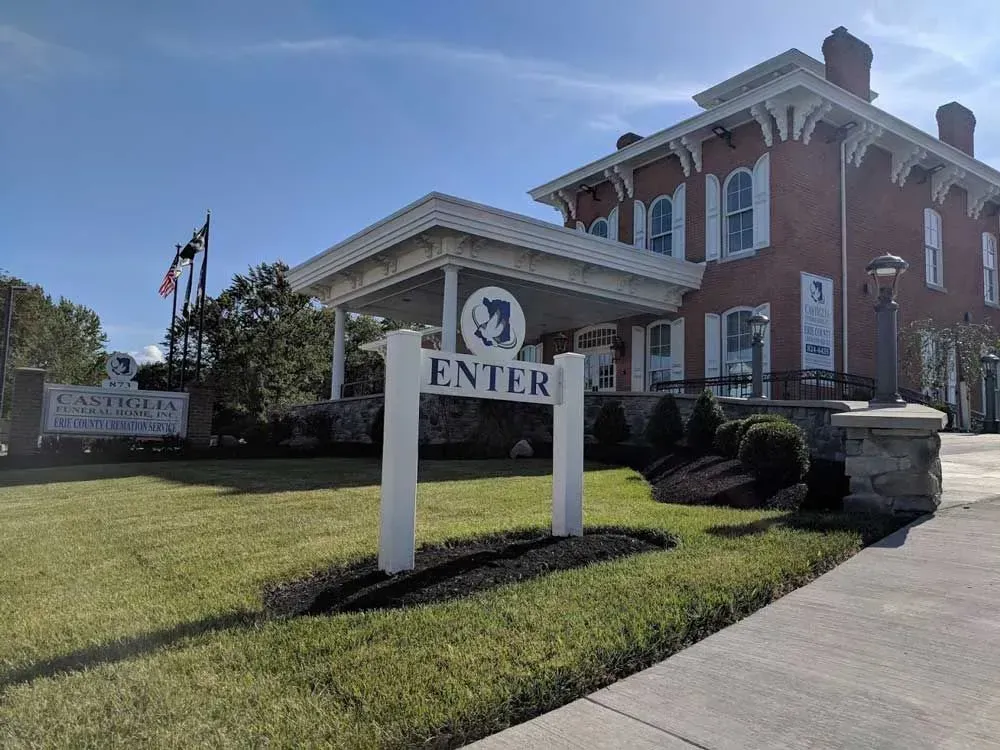 Brick building with “ENTER” sign by a sidewalk on a sunny day