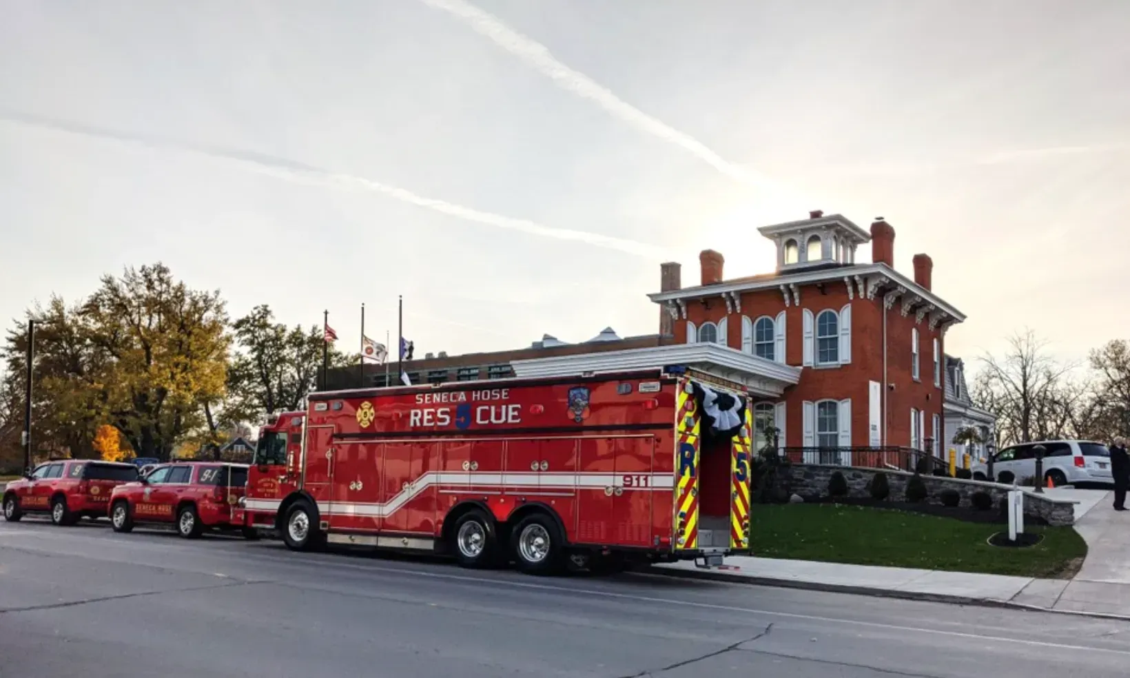 Red fire rescue truck parked beside a large brick building on a city street