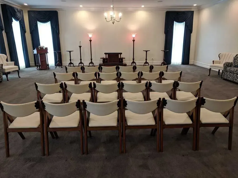 Elegant meeting room with rows of white chairs facing a small altar and candles.