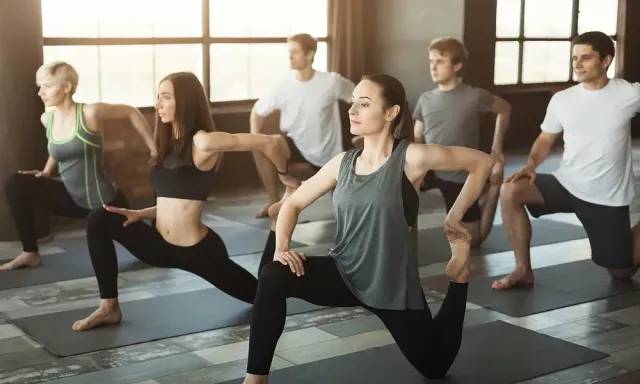 En gruppe mennesker gjør yoga sammen i et treningsstudio.