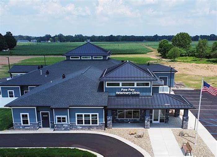 Aerial view of a dark blue and gray municipal building with an American flag, surrounded by open fields.