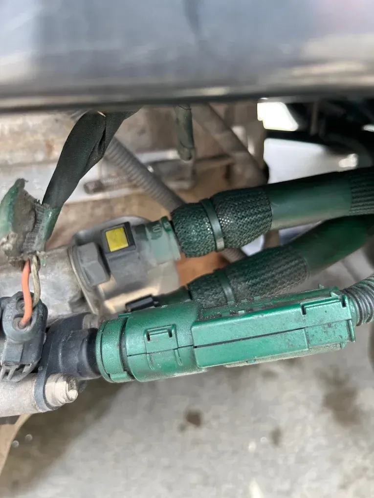 Green and black electrical connectors and wiring loom, possibly automotive, close-up.