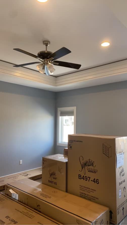 Bedroom with grey walls, ceiling fan, recessed lighting, and boxes of furniture.