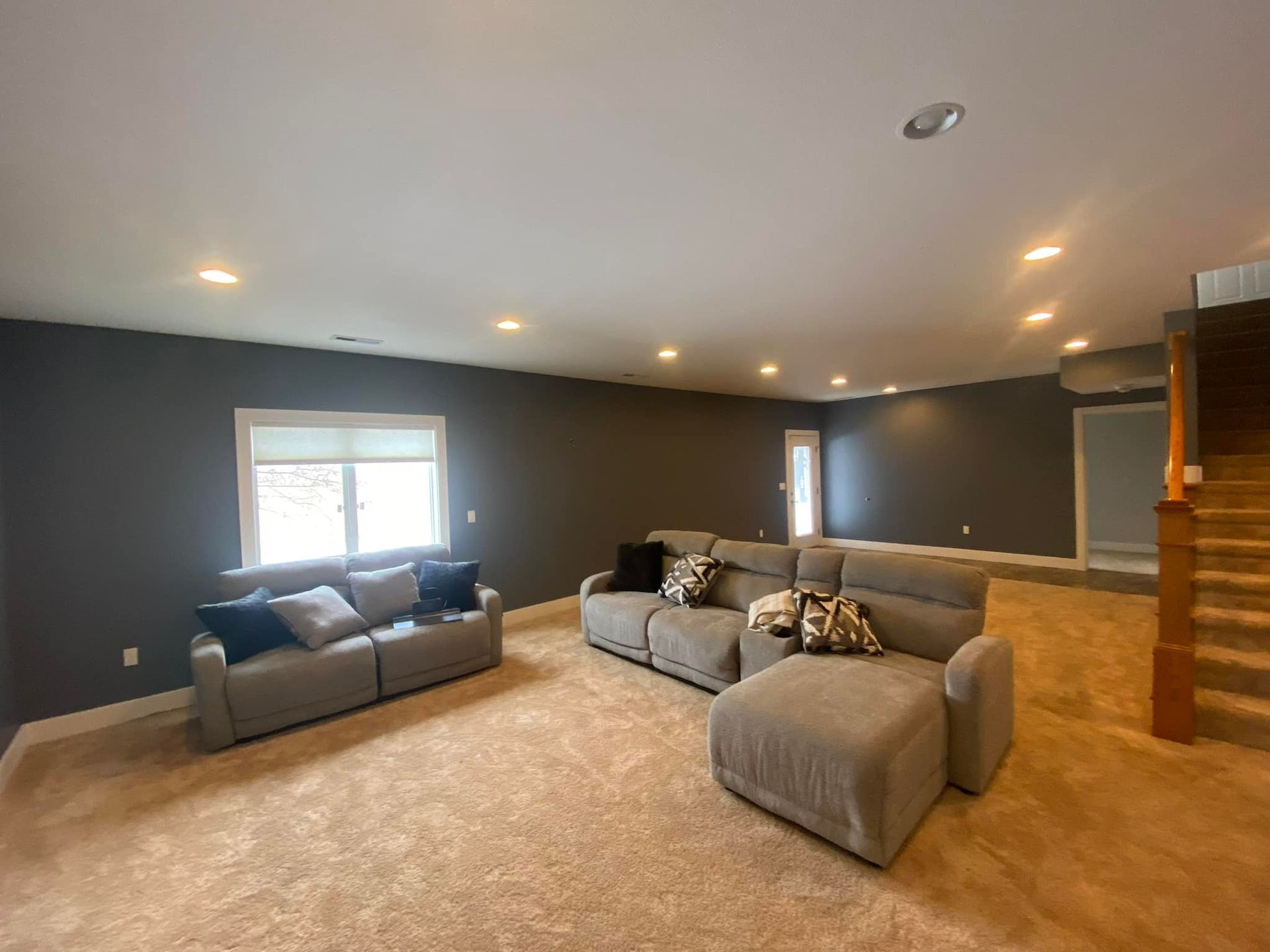 Living room with gray walls, two gray sofas, beige carpet, and recessed lighting.