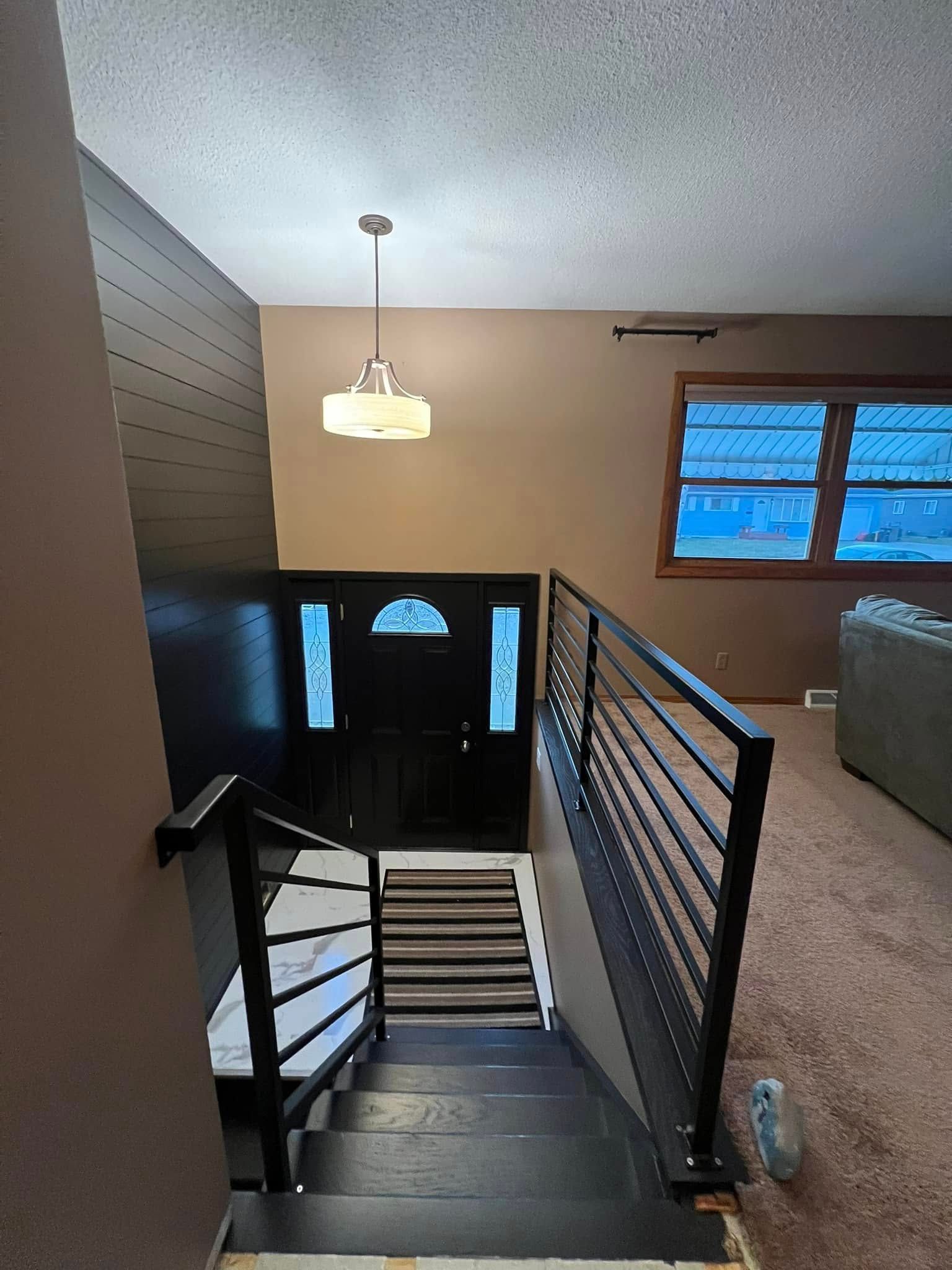 Staircase leading to a black door with frosted glass panels, lit by a pendant light.
