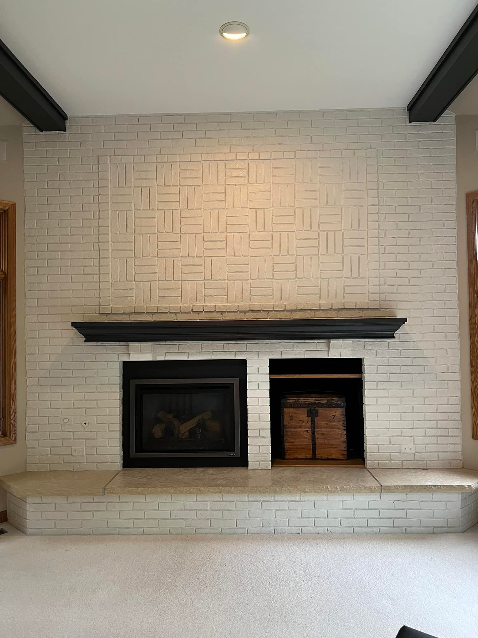 White painted brick fireplace with black mantel, built-in storage, and gas fireplace.