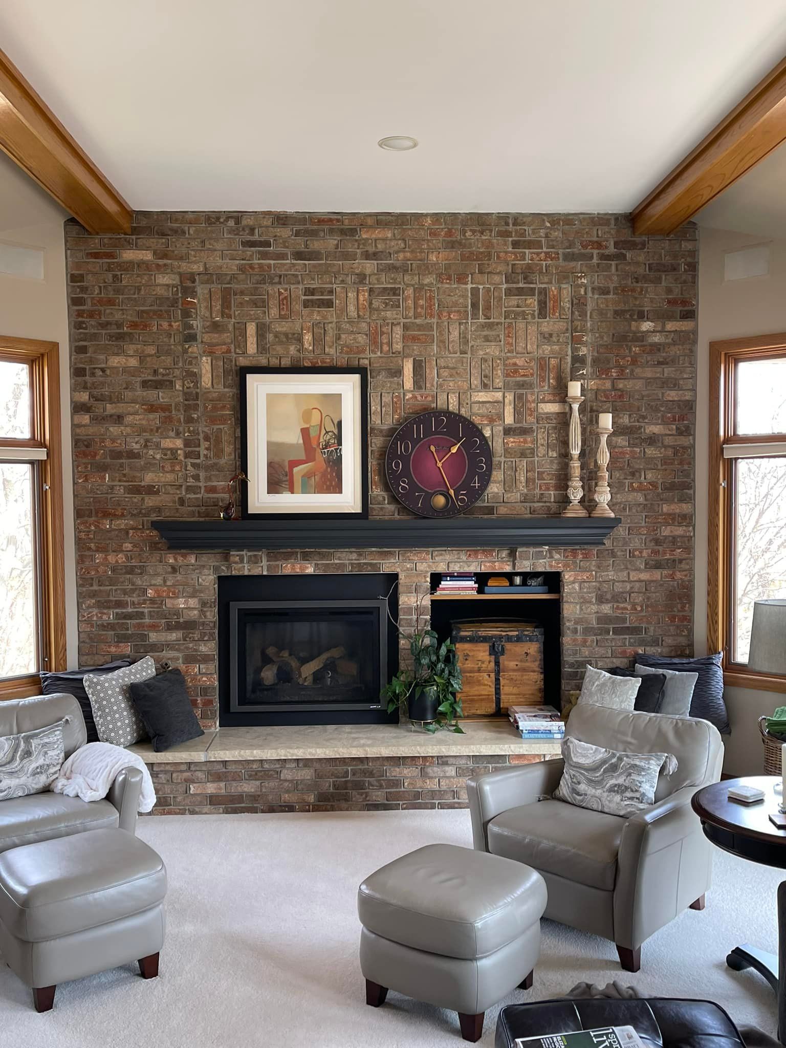 Living room with a brick fireplace, a black mantel, and light-colored furniture.