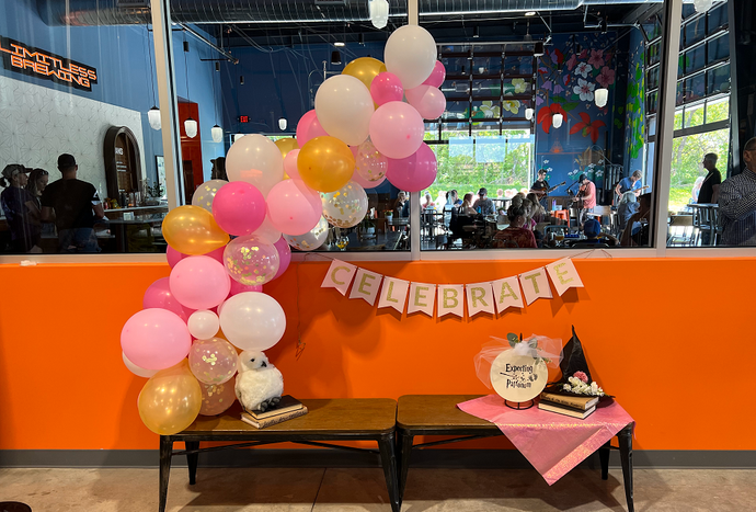 Birthday party table with pink and gold balloons and “Happy Birthday” banner in a bright room