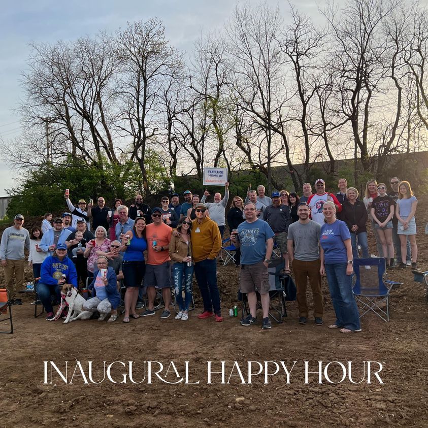 Group of people posing outdoors at dusk with “Inaugural Happy Hour” text overlay.