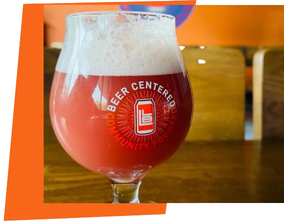 Stemmed glass of pink beer with foam on a wooden table, with a Beer Center logo