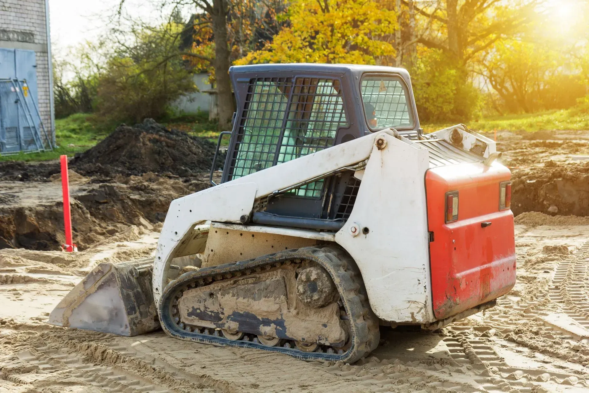 Compact track loader pushing dirt on a sunny construction site