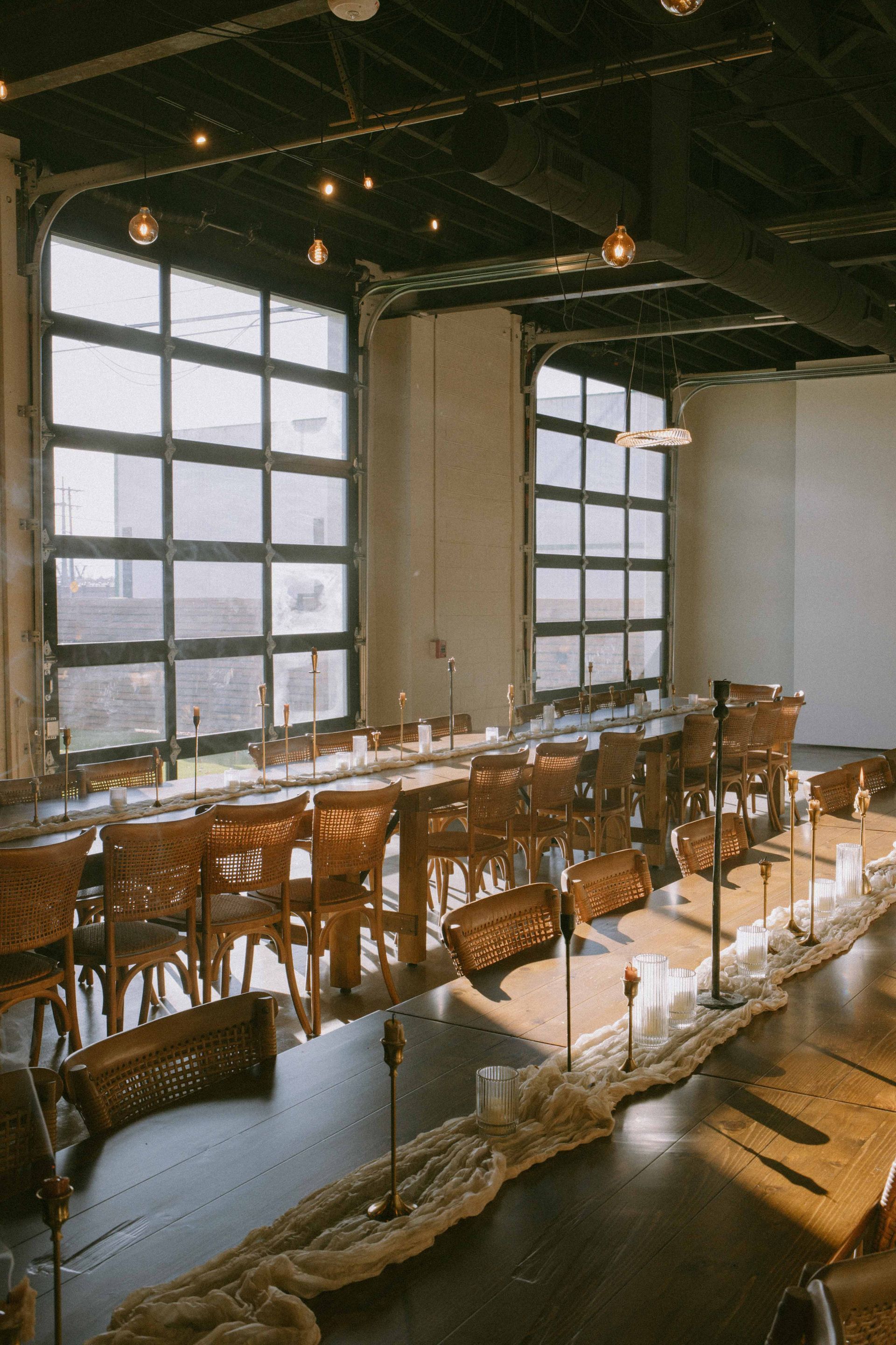 Long farm tables with candles and fabric runner set up at Bestow Events in Longmont, CO.