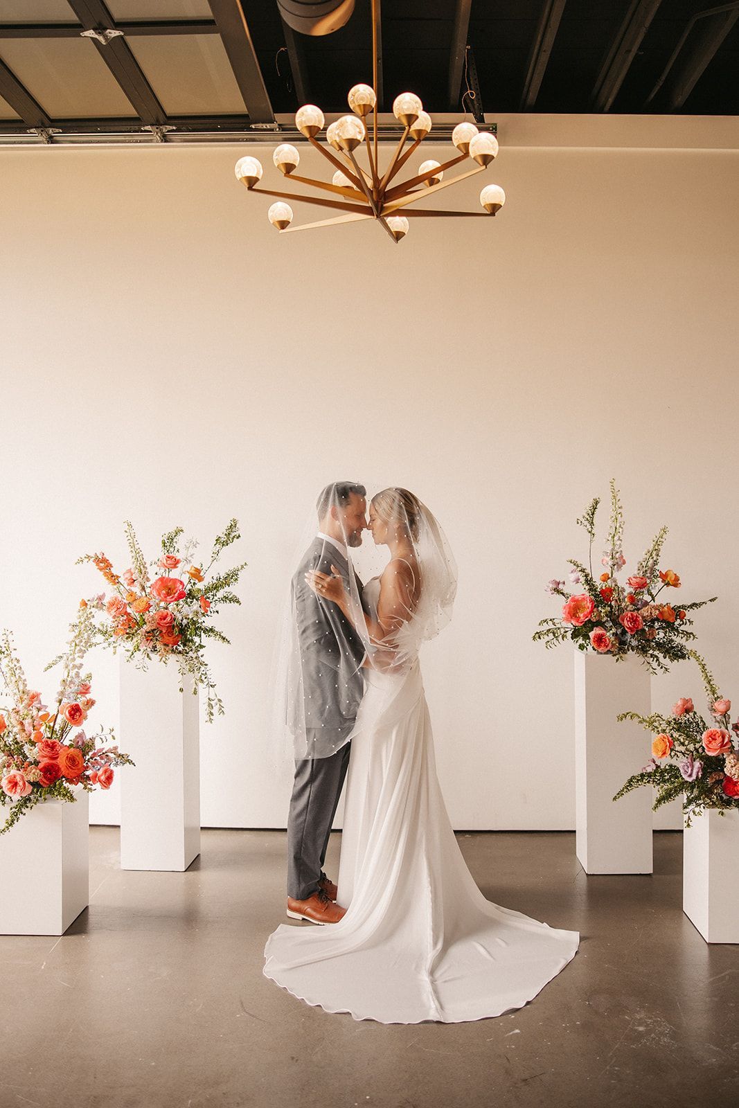 Bride and groom posing under chandelier at Bestow Events in Longmont, CO.